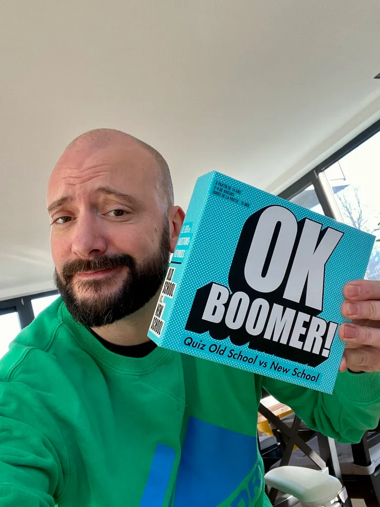 Sébastien Balieu, perplexe, tient la boîte du jeu « OK Boomer! »